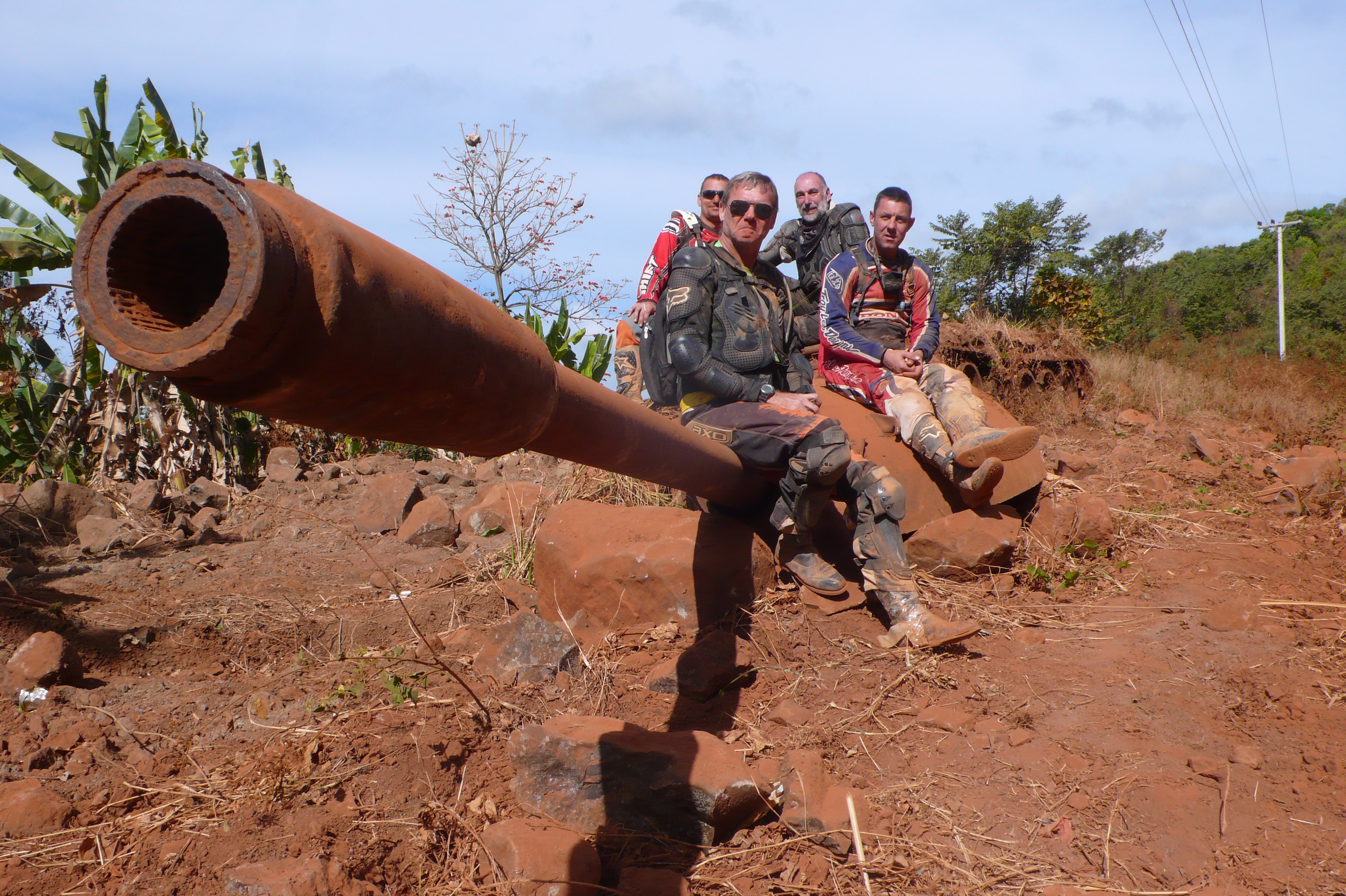Explore Indochina motorcycle tour members sitting on a destroyed tank