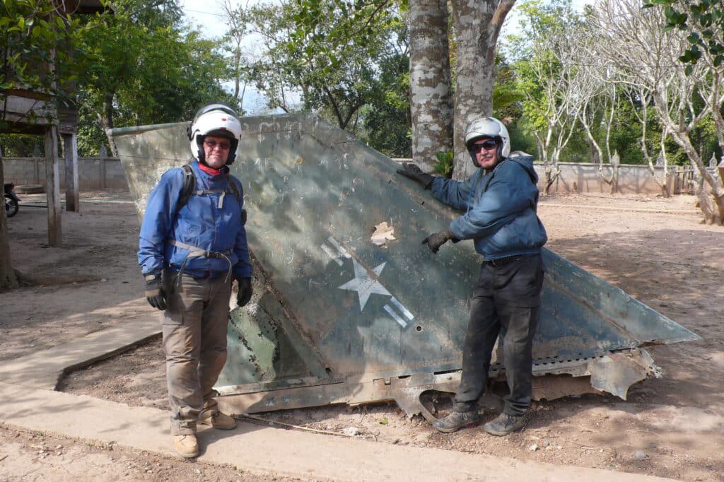 Explore Indochina riders in Laos with part of a crashed F-4 Phantom jet while on a Ho Chi Minh Trail motorcycle tour