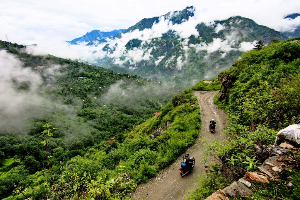 Explore Indochina riders on a forested road during a motorbike tour of the Himalayas in India