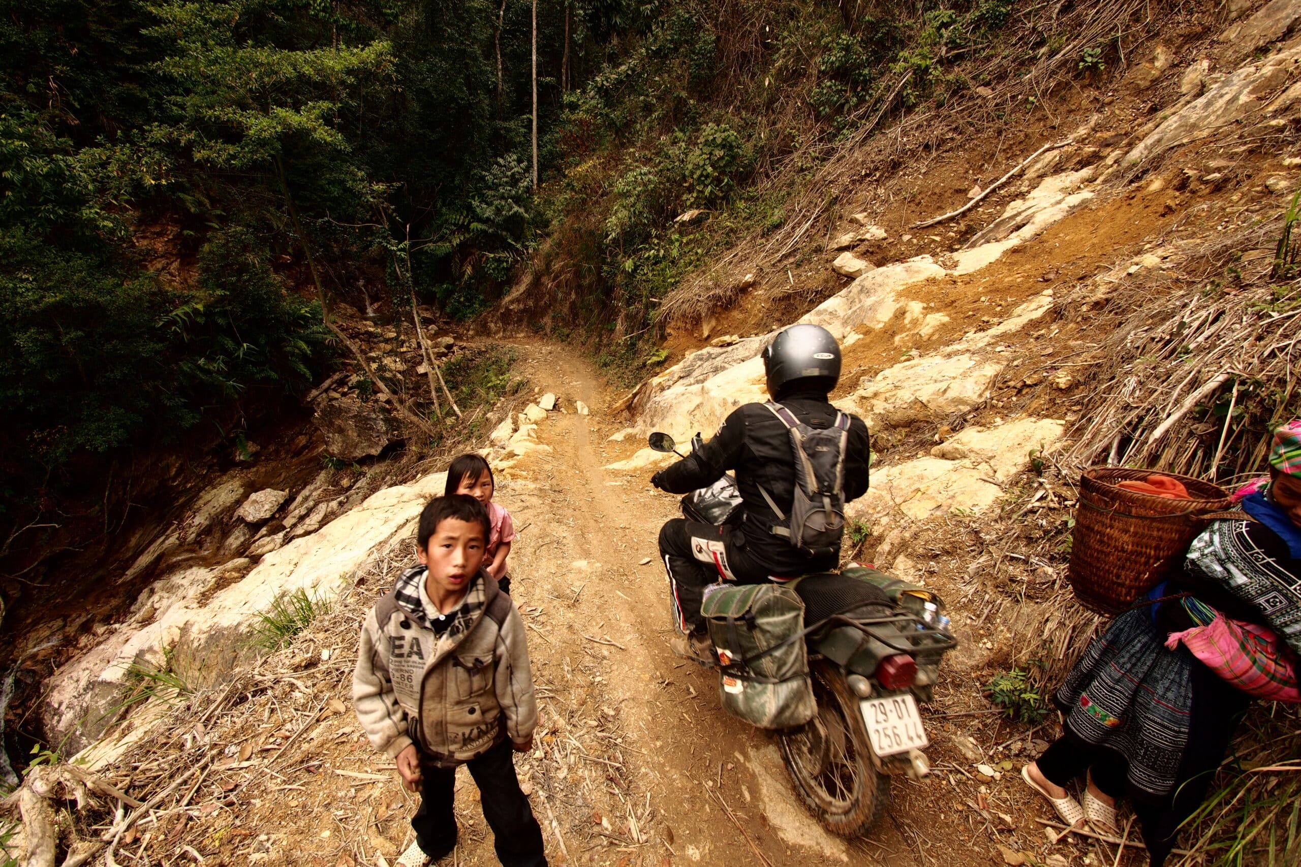 riding through the mud past some local kids in the mountains of Vietnam