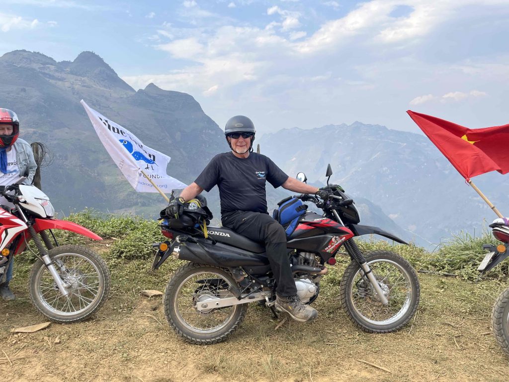 Rally Indochina rider with a Blue Dragon Children's Foundation flag