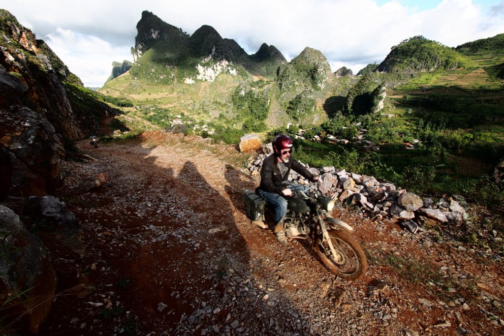 Motorcycle tour member rides past karst near Dong Van in Vietnam