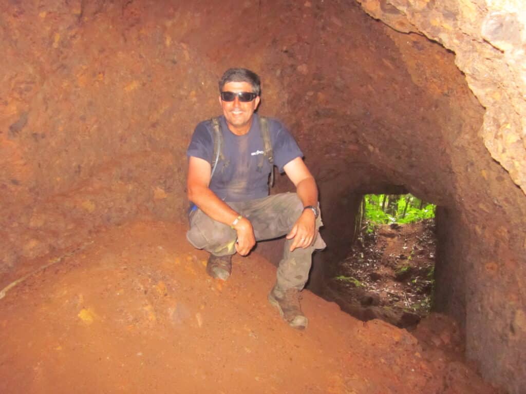 An Explore Indochina Ho Chi Minh Trail motorbike tour member explores the ruins of the former head quarters of the Vietnamese Army found in a tunnel in Laos