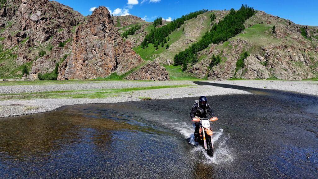 An Explore Indochina rider enjoys a river crossing north of the Orkhon Valley during a Mongolia motorcycle tour