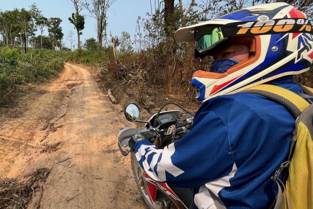 An Explore Indochina rider enjoys dirt tracks while on a motorbike tour of the Ho Chi Minh Trail in Laos